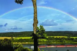 Stunning rainbow over the river with barge going by taken from the balcony of Big Timber River Cabins