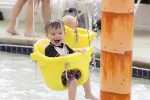 Baby in yellow swing in the children's splash area at Big Splash Adventure