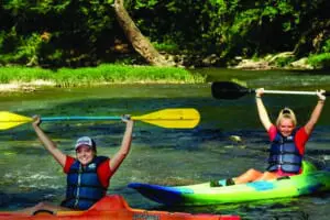 People kayaking down the Blue River with their arms up and having fun.
