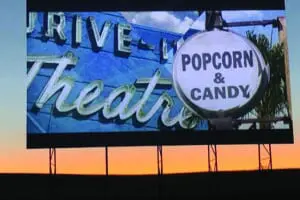 Drive-In movie screen showing retro sign and promoting Popcorn adn candy at the snack bar.