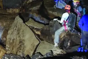 Deep Darkness explore group climbing down some breakdown rocks