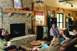 Friends sitting by a fireplace on cozy leather couches