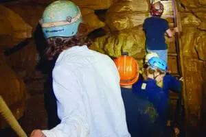 Team of adverture seeking teens climbing a ladder as they explore Bluespring Caverns
