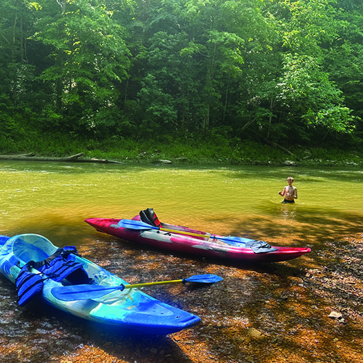 Kayakers taking a break along the river beach to cool off in the water.