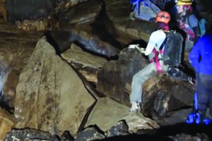 Deep Darkness explore group climbing down some breakdown rocks